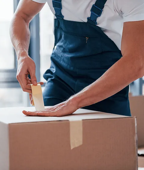 Hombre cerrando caja con cinta